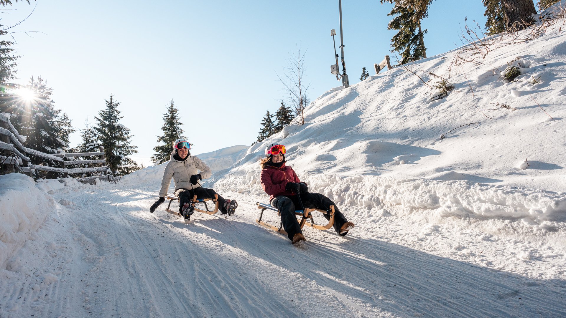 Lahnerhof: our nature and wellness hotel near Sterzing Two people sledding on a snowy path on a sunny day