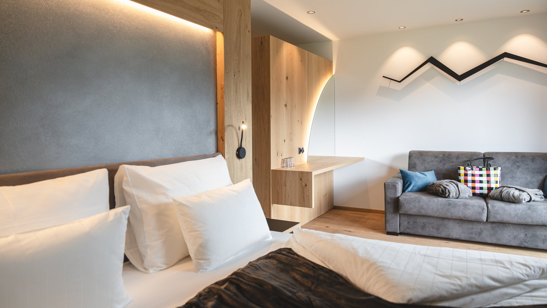 Aktivurlaub am Rosskopf bei Sterzing: Hotel Lahnerhof Modernes Hotelzimmer mit gemütlichem Bett und Sofa mit Taschen