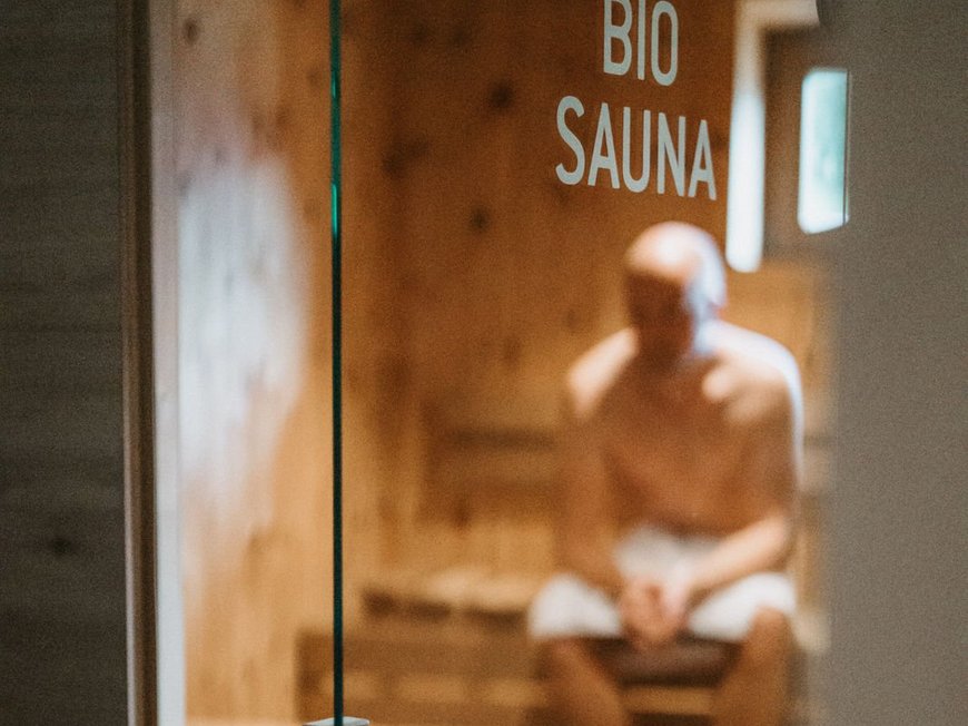 Cercate un hotel a Vipiteno con spa? Benvenuti al Lahnerhof! Uomo seduto nella sauna bio dietro la porta di vetro
