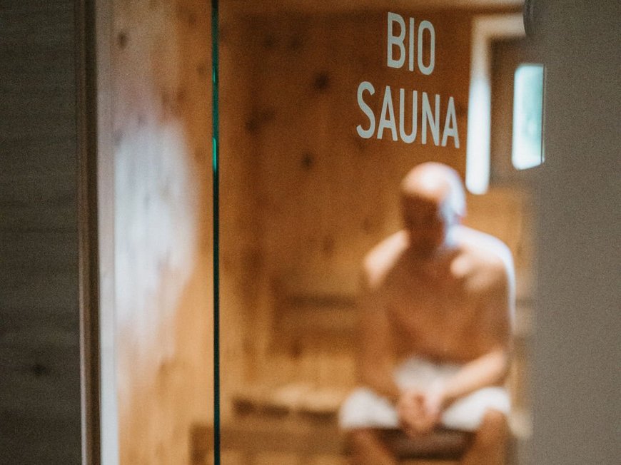 Our hiking and wellness hotel near Sterzing: Lahnerhof Man sitting inside a bio sauna behind a glass door