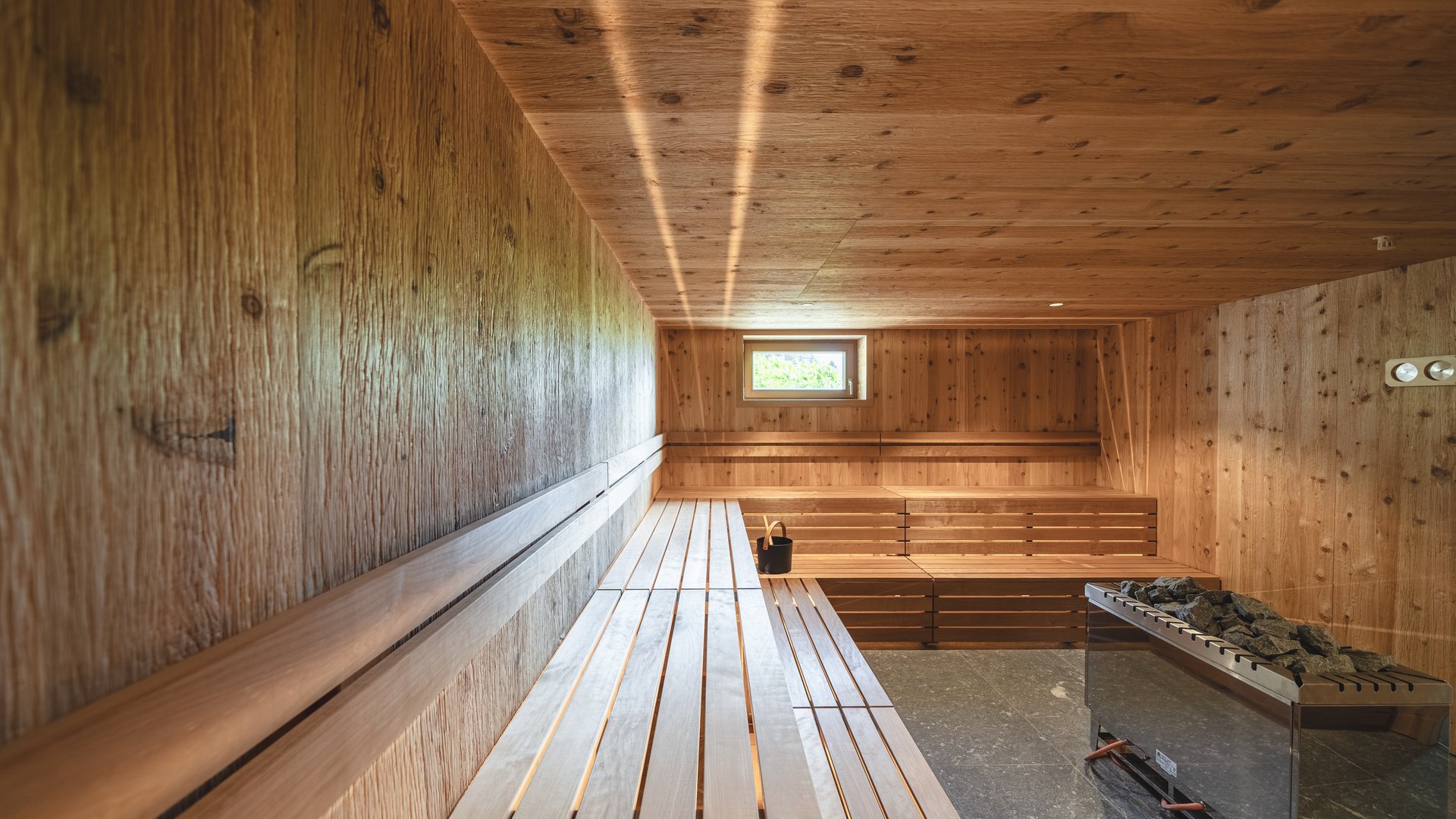 Our hiking and wellness hotel near Sterzing: Lahnerhof Bright wooden sauna with bench, window, and sauna heater