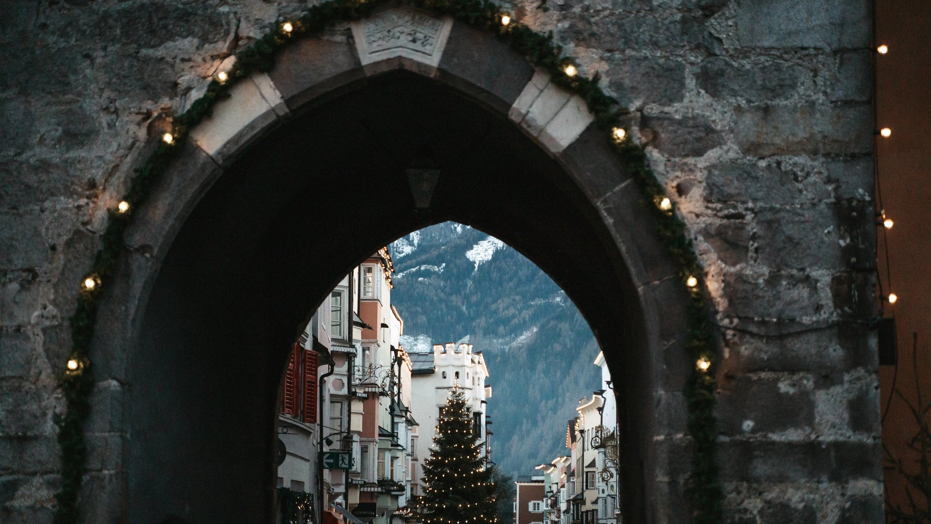 Lahnerhof: Natur- und Wellnesshotel bei Sterzing Beleuchteter Steinbogen mit Blick auf einen Weihnachtsbaum in einer Bergstadt