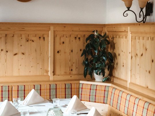 South Tyrolean specialities at our restaurant near Sterzing Cozy dining area with wooden walls, heart decoration, and set table