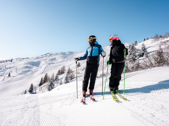 Lahnerhof: our hotel near Sterzing on Monte Cavallo/Rosskopf Two skiers wearing helmets and goggles on snowy slope under clear blue sky