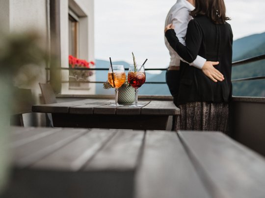 South Tyrolean specialities at our restaurant near Sterzing Couple hugging on balcony with two Aperol Spritz drinks on table