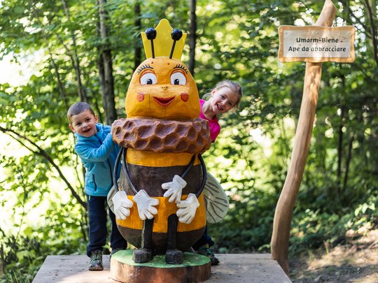 Hiking in Ratschings and surroundings Two children beside a large bee statue in a forest