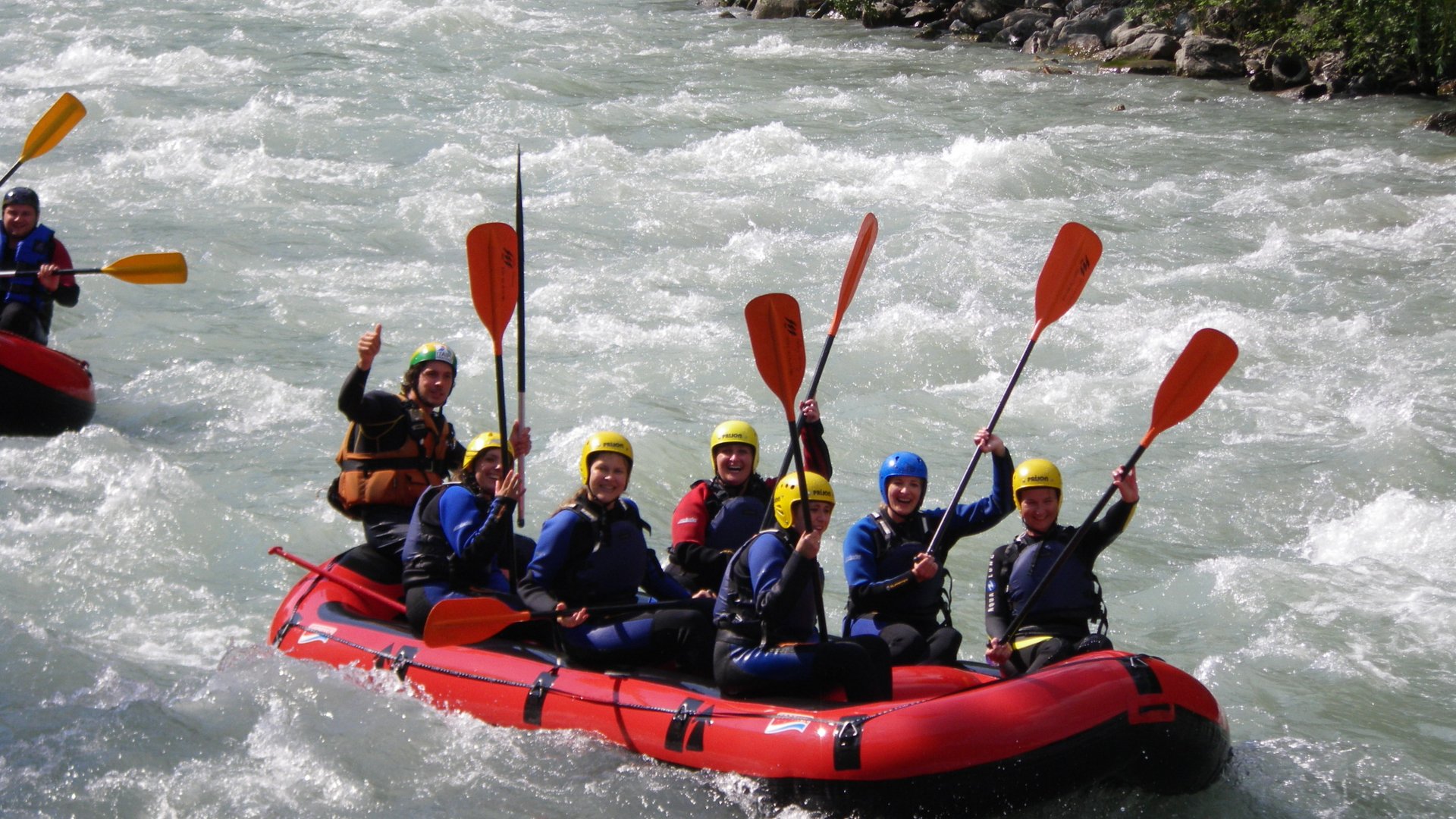 Hiking in Ratschings and surroundings Group rafting on a rapid river with raised paddles