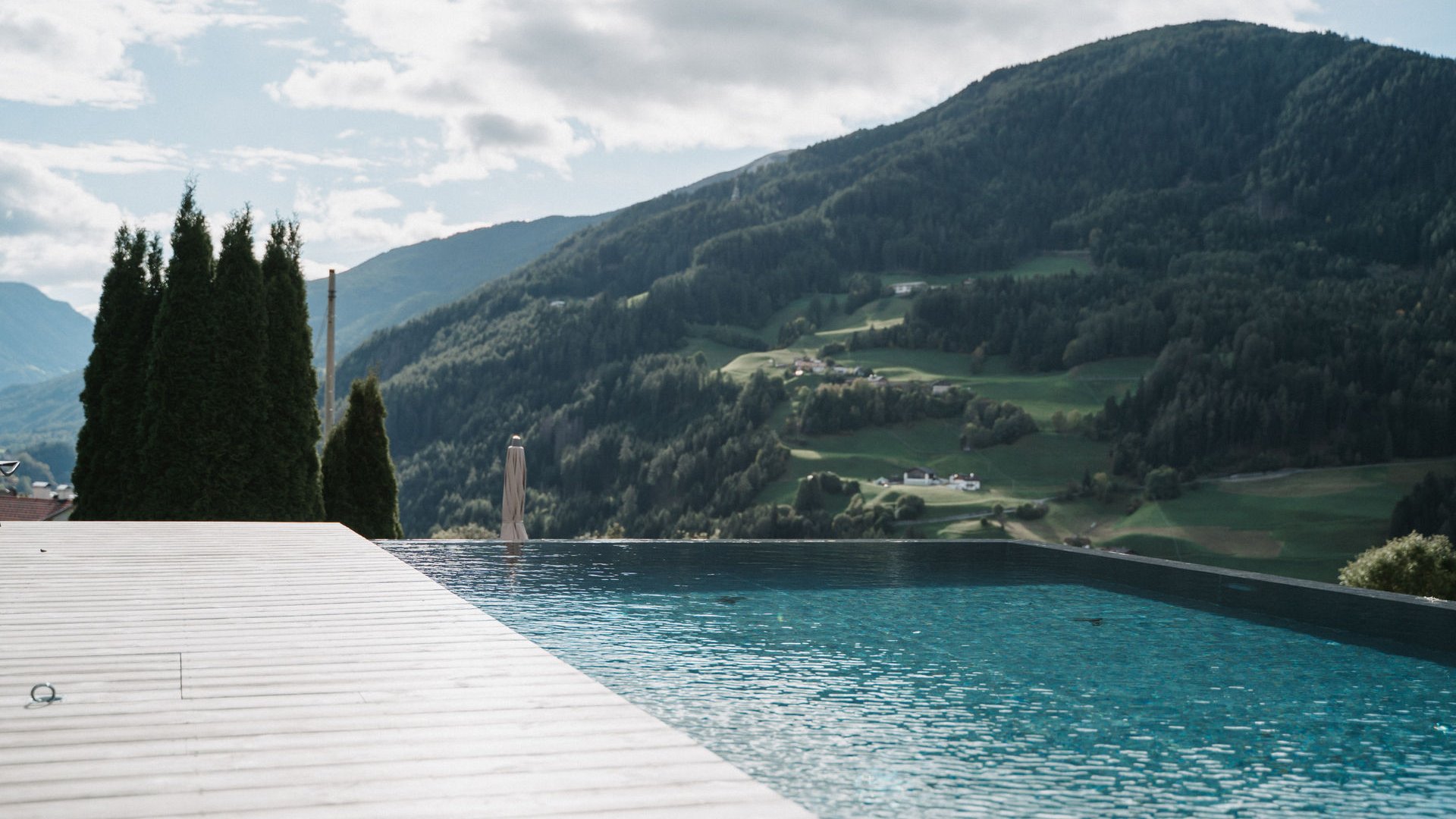 Lahnerhof: our nature and wellness hotel near Sterzing Infinity pool overlooking mountains under a cloudy sky