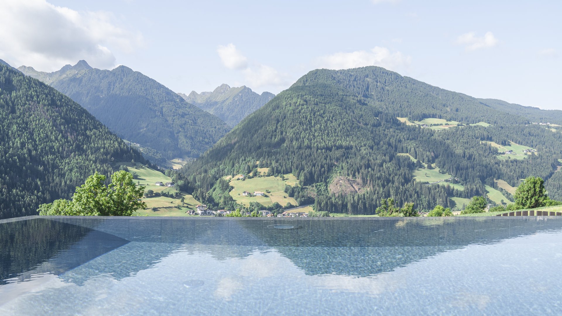 Infinity-Pool mit Blick auf grüne Berge und bewölkten Himmel