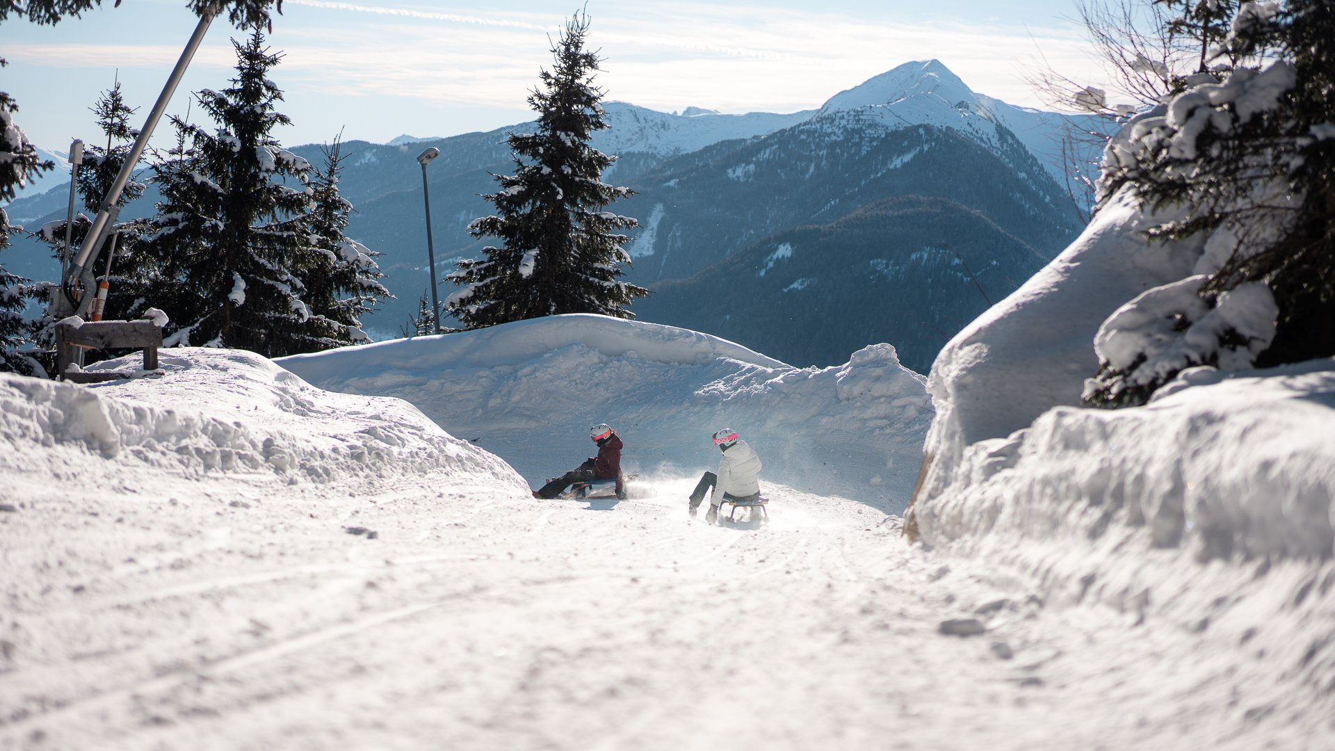 Lahnerhof: Natur- und Wellnesshotel bei Sterzing Zwei Personen rodeln auf einer verschneiten Piste vor einer Bergkulisse