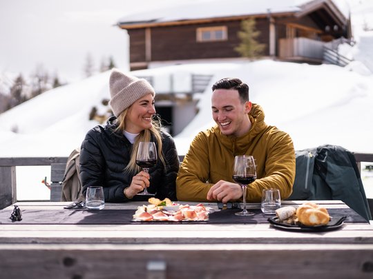 Lahnerhof: our hotel near Sterzing on Monte Cavallo/Rosskopf Couple enjoying wine and food outdoors in the snow by a cabin