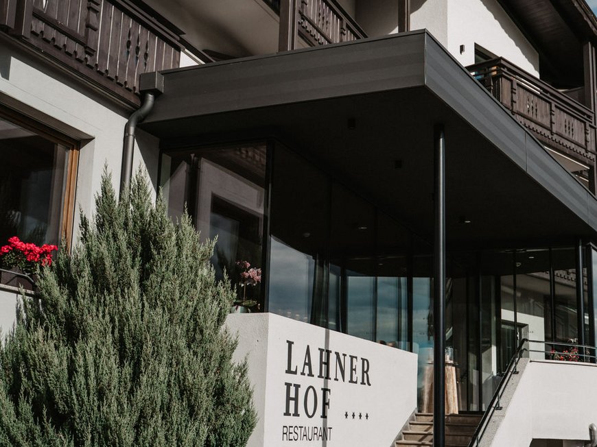 Vacanze nel nostro hotel con piscina a Vipiteno benvenuti! Ingresso dell'hotel Lahner Hof con scale e balconi sotto il cielo blu