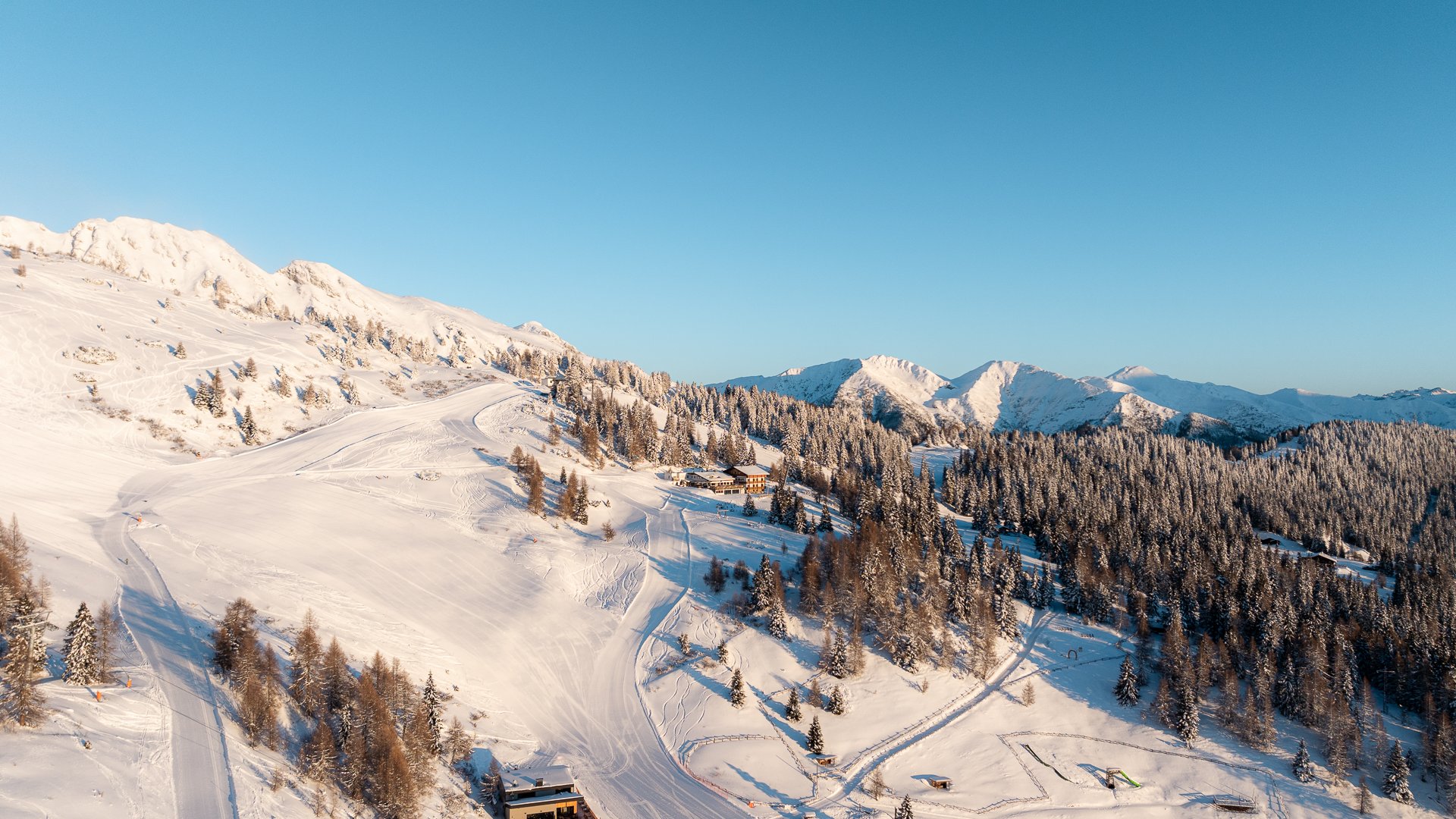 Lahnerhof: Natur- und Wellnesshotel bei Sterzing Verschneite Skipisten und Berghütten zwischen bewaldeten Bergen unter blauem Himmel