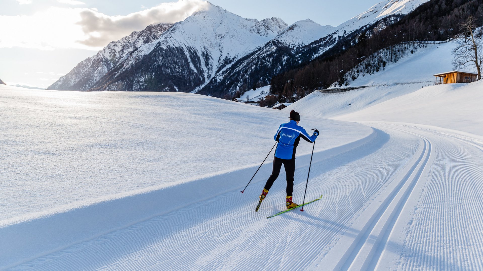 Lahnerhof: our hotel near Sterzing on Monte Cavallo/Rosskopf Cross-country skier in blue jacket on sunny trail with snowy mountains background