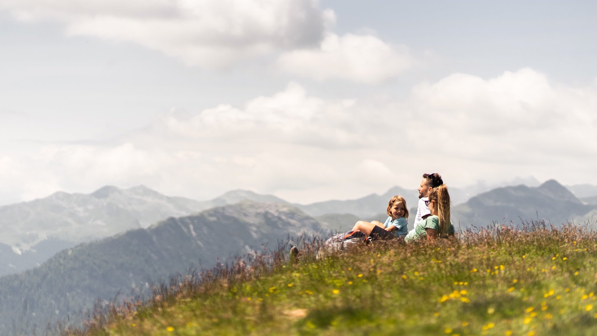 Wanderung auf den Rosskopf und mehr Familie sitzt auf einer Wiese in den Bergen bei sonnigem Wetter