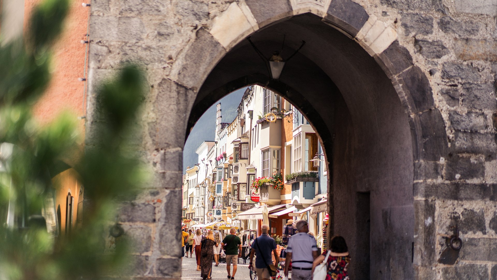 Hiking in Ratschings and surroundings Historic stone archway overlooking a busy shopping street