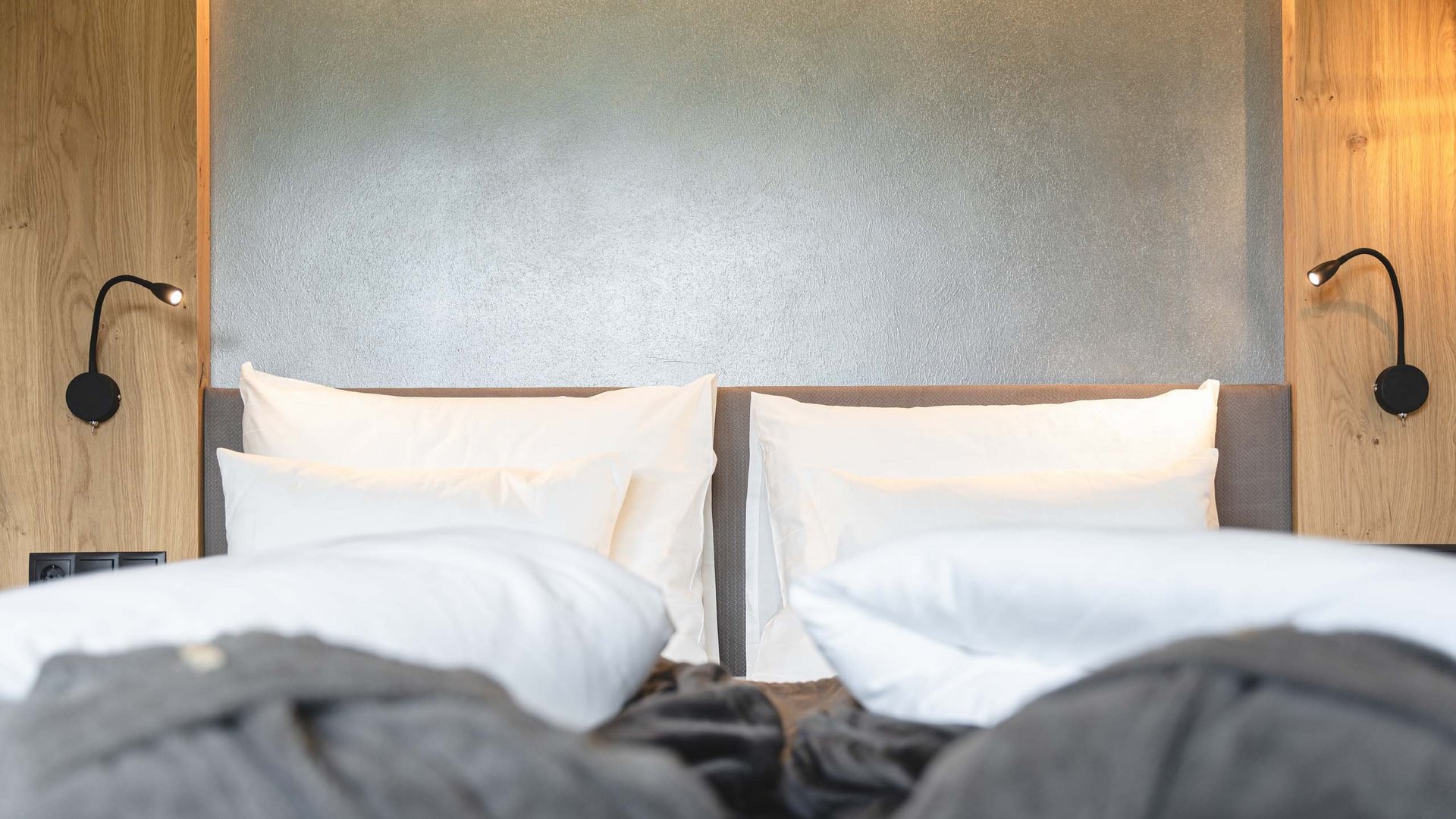 Lahnerhof, Ihr Hotel bei Sterzing Modernes Doppelbett mit weißen Kissen und grauen Decken in Hotelzimmer