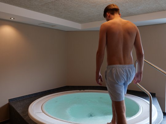 Cercate un hotel a Vipiteno con spa? Benvenuti al Lahnerhof! Uomo entra nella vasca idromassaggio in una stanza moderna con lampada rotonda a soffitto