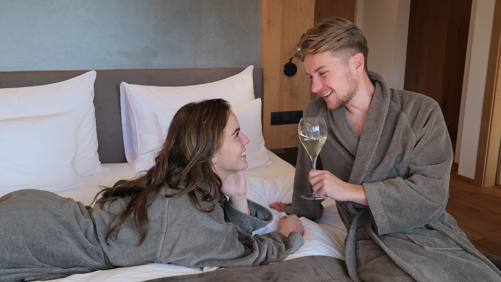 Lahnerhof: our nature and wellness hotel near Sterzing Couple in robes relaxing on bed with wine in cozy bedroom