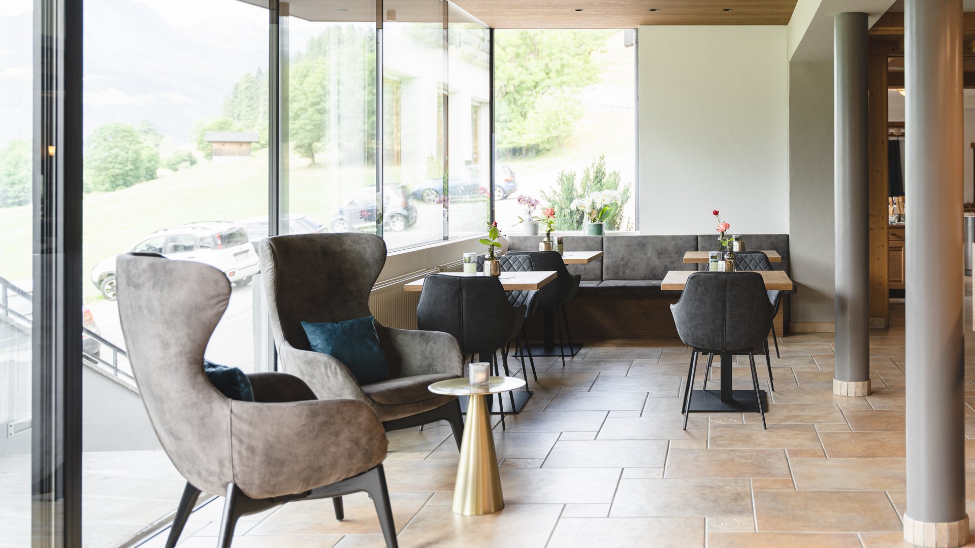 Lounge moderna con poltrone grigie e vista sulle montagne dalle finestre