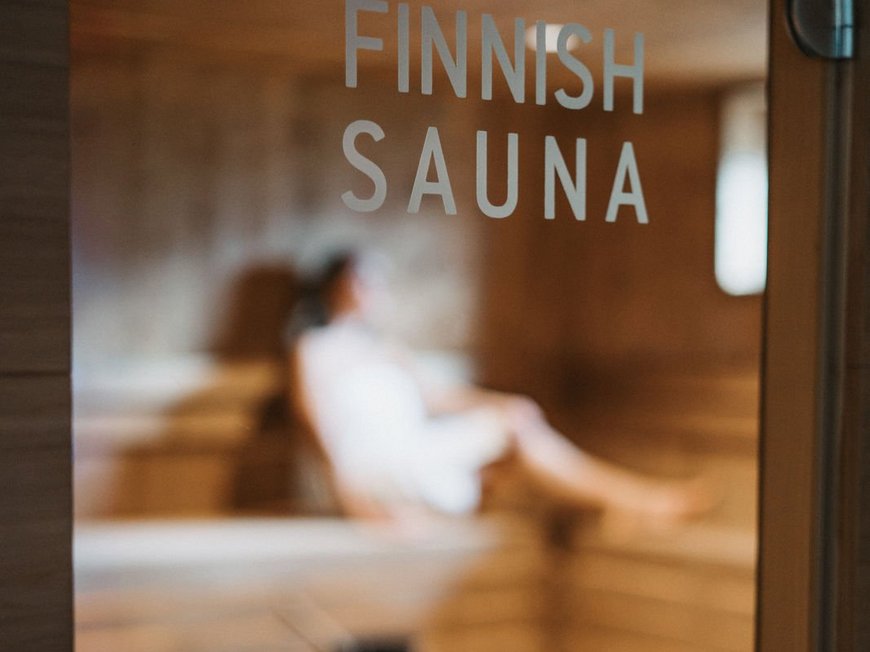 Wander- und Wellnesshotel bei Sterzing: der Lahnerhof Tür mit Aufschrift Finnische Sauna und unscharfe Person im Inneren