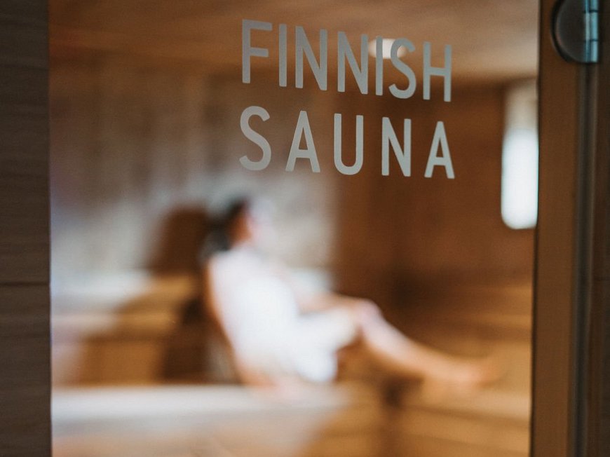 Our hiking and wellness hotel near Sterzing: Lahnerhof Door with Finnish Sauna sign and blurred person inside sauna