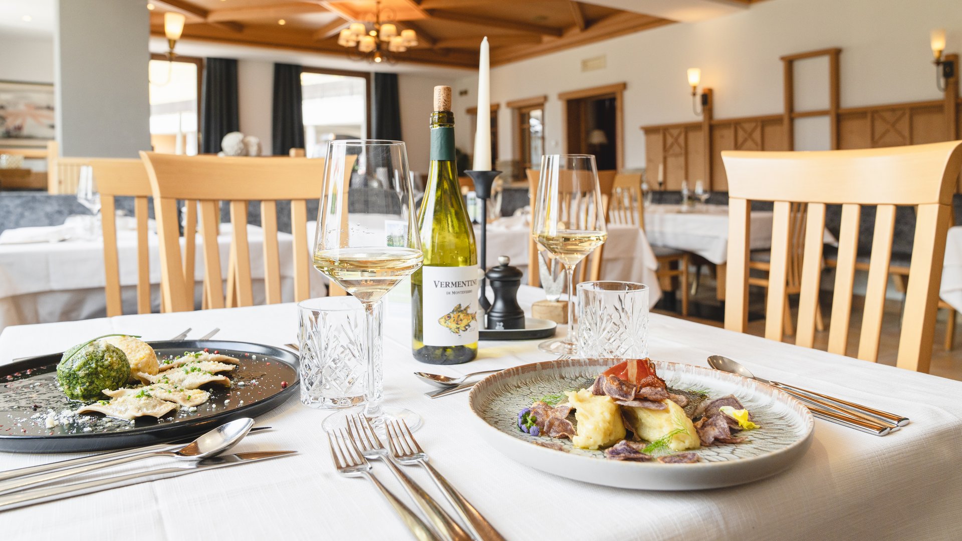 Lahnerhof: our nature and wellness hotel near Sterzing Elegant restaurant table with two gourmet dishes and white wine glasses