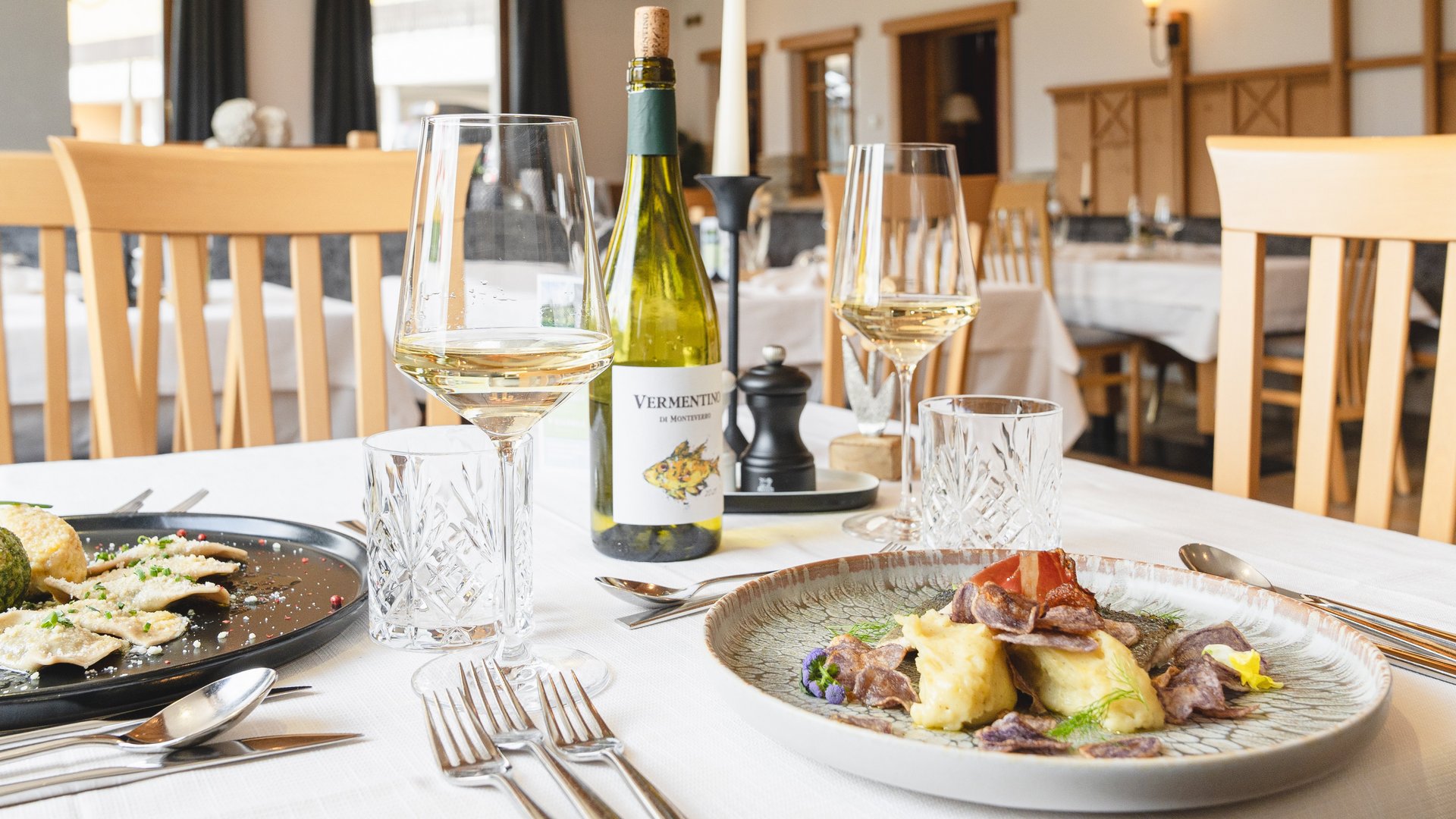 Delizioso ed entusiasmante Ristorante elegante con due piatti gourmet e vino bianco su tavolo apparecchiato