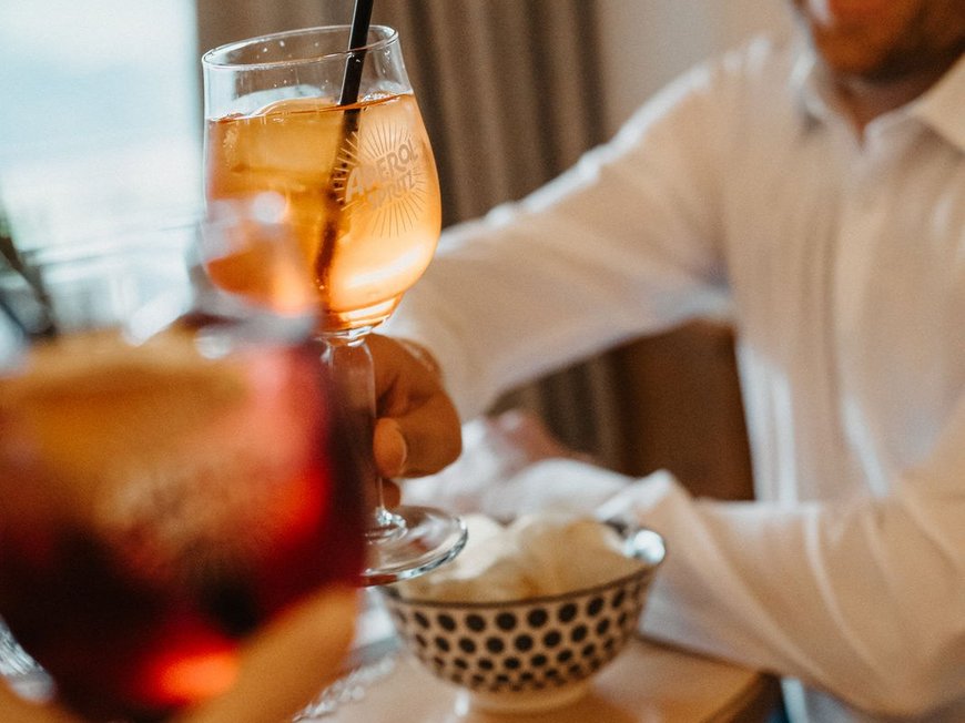 South Tyrolean specialities at our restaurant near Sterzing Man clinks Aperol Spritz drink at table