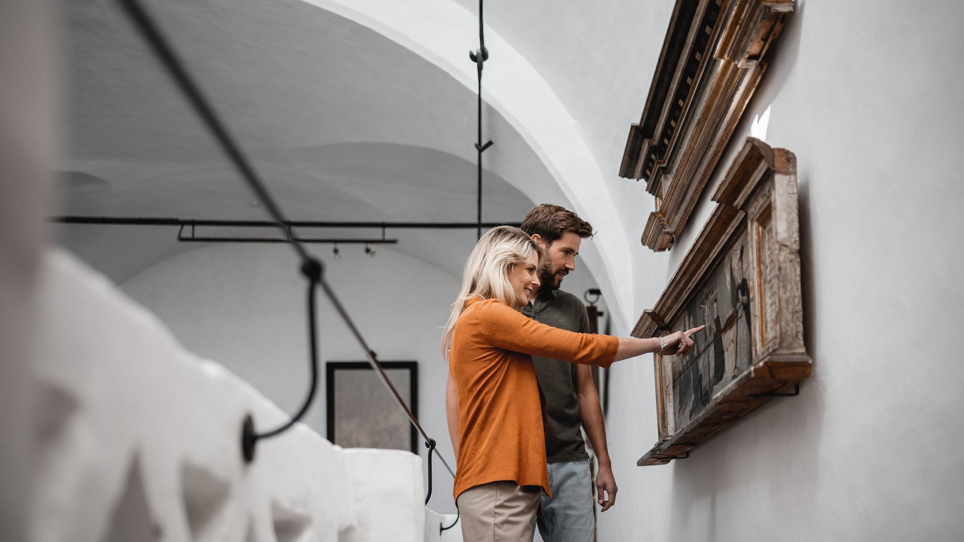 Vi piacciono le escursioni con le ciaspole a Vipiteno? Coppia osserva e indica un dipinto in una galleria con pareti bianche