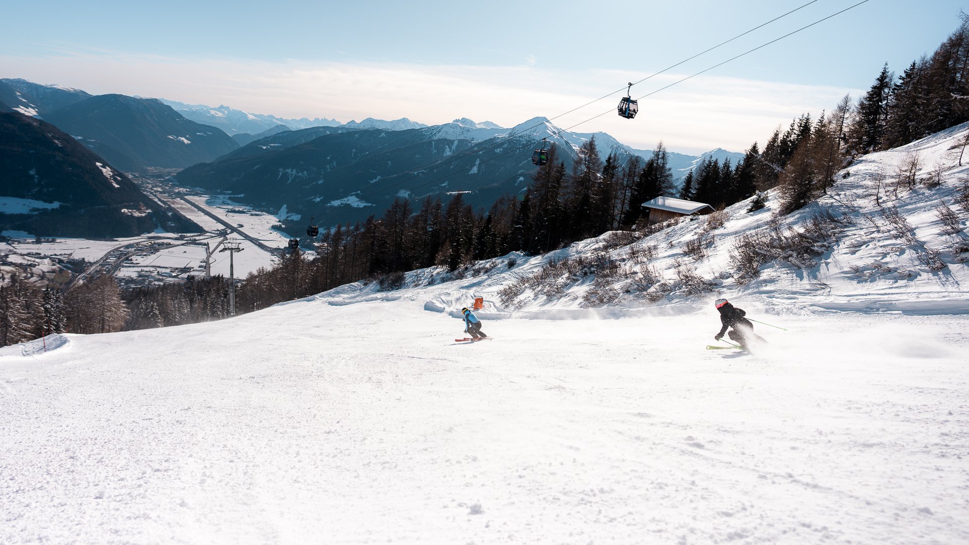 Wanderung auf den Rosskopf und mehr Skifahrer auf verschneiter Piste mit Berggondeln und Alpenpanorama