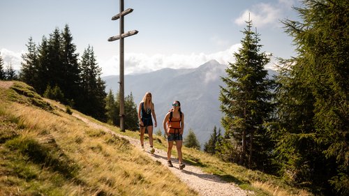 Il Lahnerhof, il vostro hotel a Vipiteno e dintorni Due escursioniste su sentiero di montagna vicino a grande croce di legno