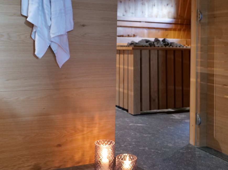 Il Lahnerhof, il vostro hotel a Vipiteno e dintorni Asciugamani bianchi appesi vicino a una sauna con candele accese di fronte