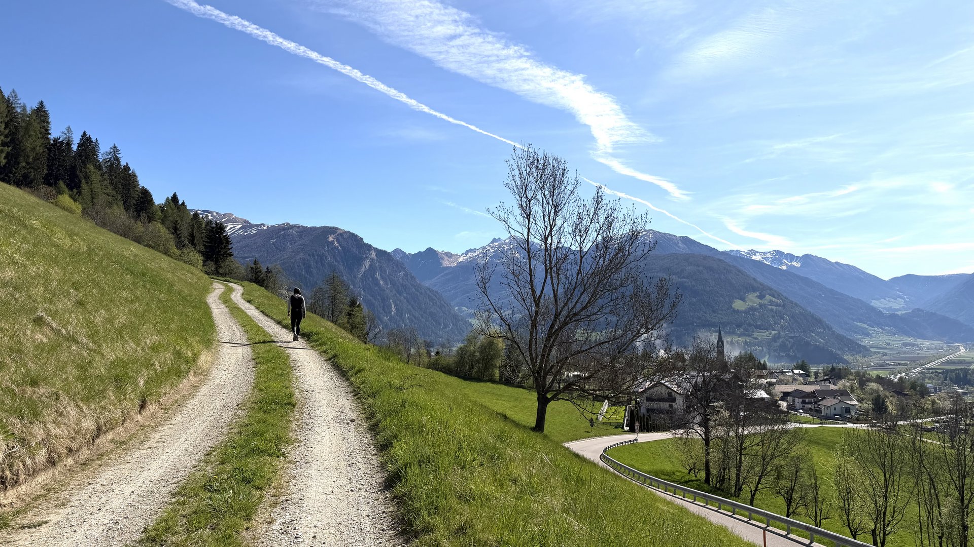 Entspannend und erlebnisreich Wanderer auf Bergpfad mit Blick auf Tal und schneebedeckte Berge unter blauem Himmel