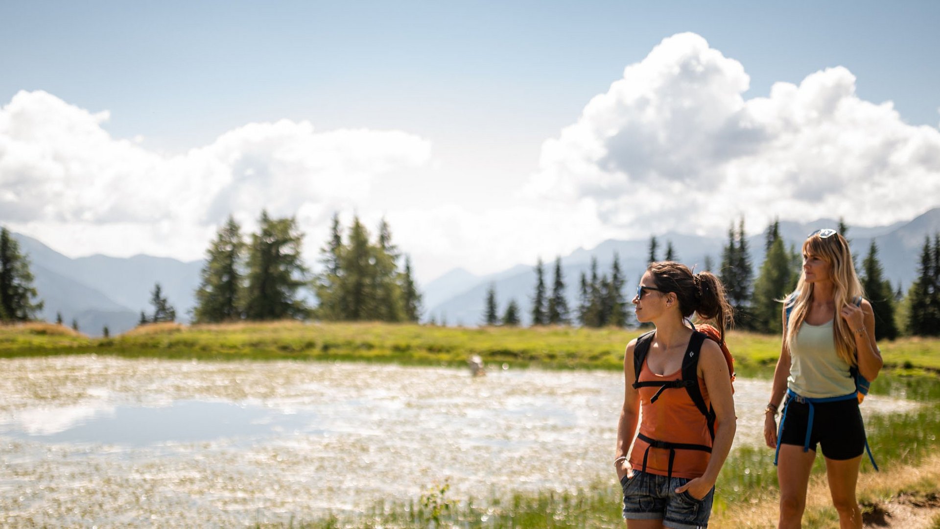 Delizioso ed entusiasmante Due donne camminano su un sentiero accanto a un piccolo lago in montagna