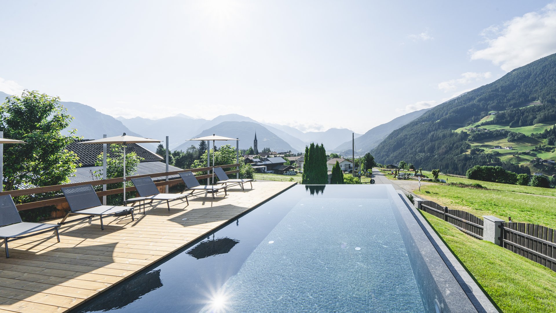 Piscina a sfioro con lettini e vista sulle montagne sotto un cielo limpido