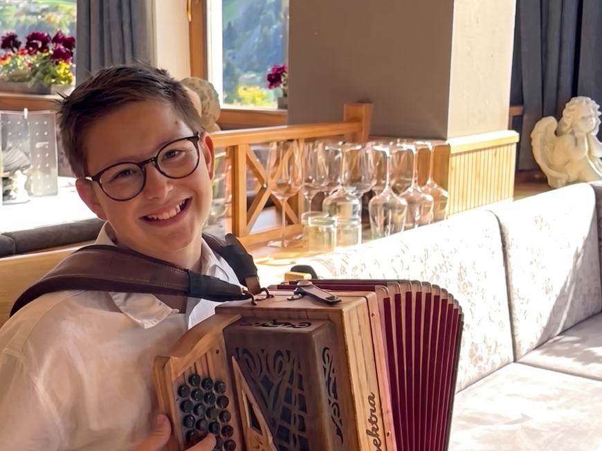Our hiking and wellness hotel near Sterzing: Lahnerhof Boy with glasses playing accordion in bright room with window view
