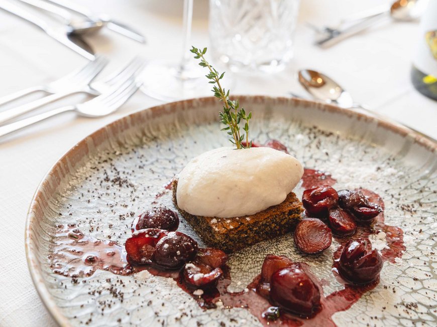 Delizioso ed entusiasmante Dessert con panna montata, ciliegie e ramo di erbe su piatto