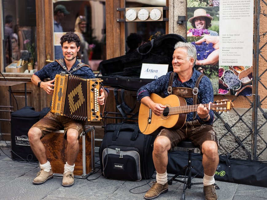 Wanderung auf den Rosskopf und mehr Zwei Musiker in traditioneller Kleidung spielen Akkordeon und Gitarre auf der Straße.