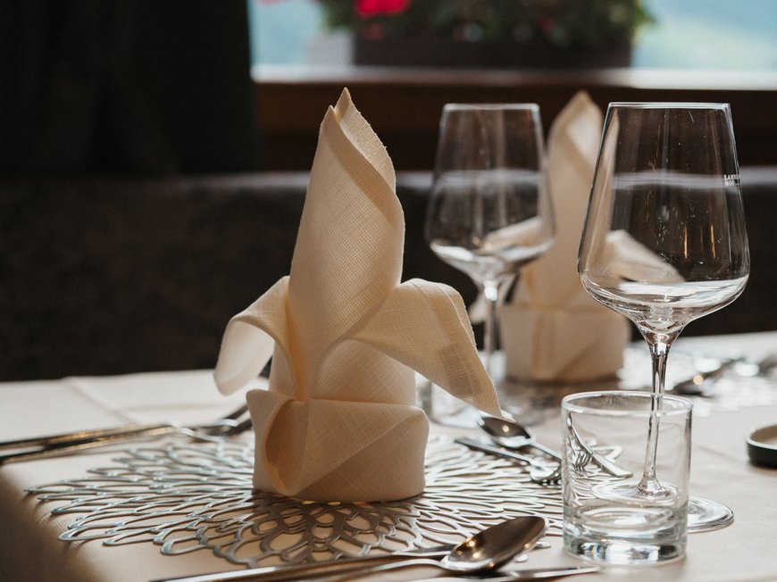 South Tyrolean specialities at our restaurant near Sterzing Elegant set table with napkins, glasses, and flowers in the background