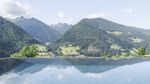 Il Lahnerhof, il vostro hotel a Vipiteno e dintorni Piscina a sfioro con vista sulle montagne verdi e valle in estate